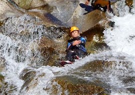 A man sliding down a natural slide in the Chassezac Canyon with the provider Cévèn'Adventure.