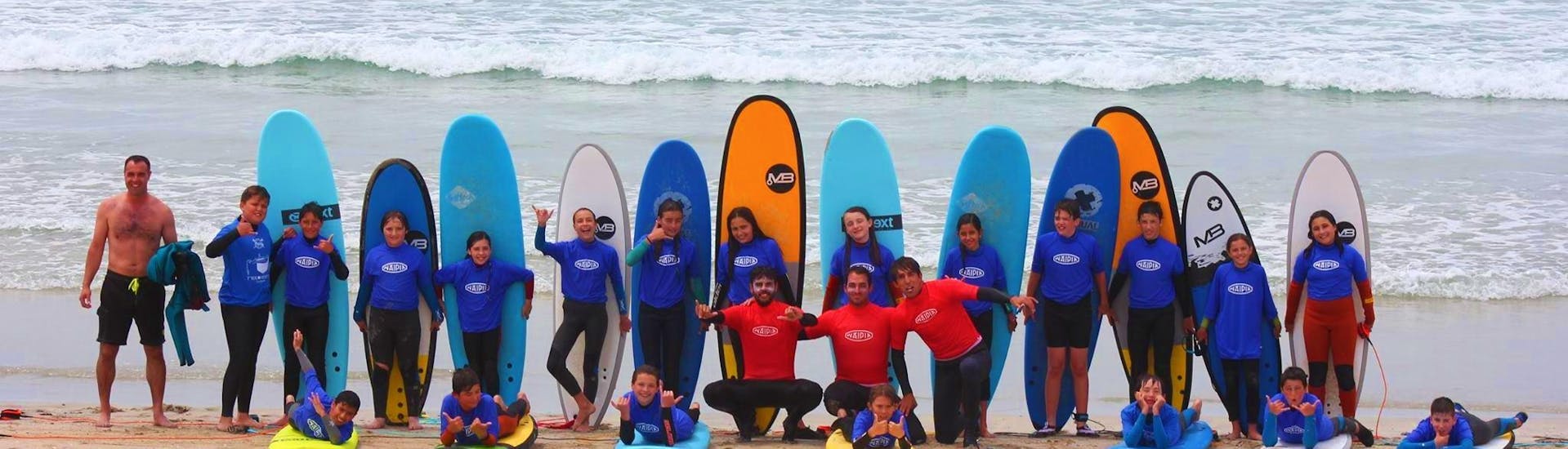 A group poses with their boards during their surf course at La Lanzada with Waipia Surf School.
