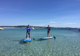 Two people do a stand up paddleboarding tour in the Rias Bajas with Waipia Surf School.