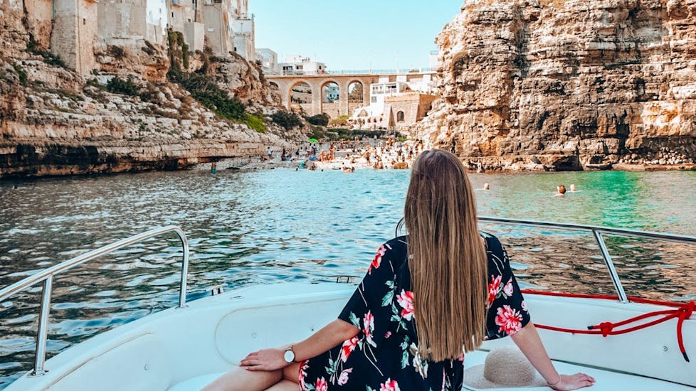 A girl is admiring Polignano from the boat during the boat trip to the Polignano a Mare caves with aperitif with Pugliamare.