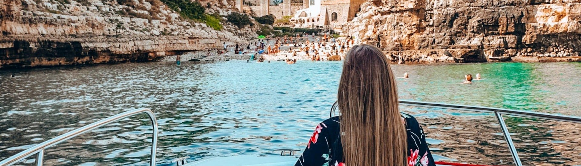 Una ragazza sta ammirando Polignano dal mare durante il giro in barca alle grotte di Polignano con aperitivo.