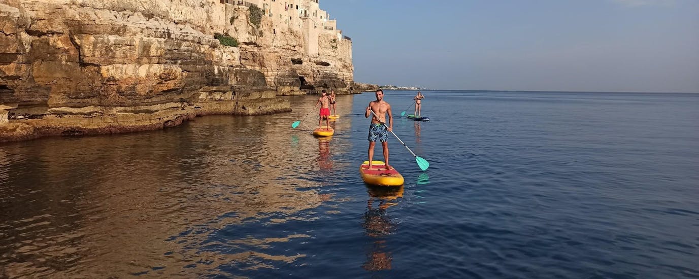 A group of friends having fun with the Stand Up Paddle Tour to the Polignano a Mare Caves.