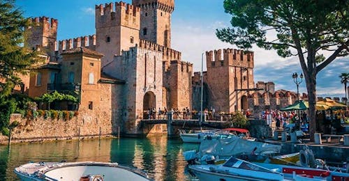 Balade en bateau sur le lac de Garda le long de la péninsule de Sirmione avec Garda Tours Les vedettes de Sirmione Boats arrêtées au port devant le château en attendant l'arrivée des clients avant une balade en bateau le long de la péninsule de Sirmione.