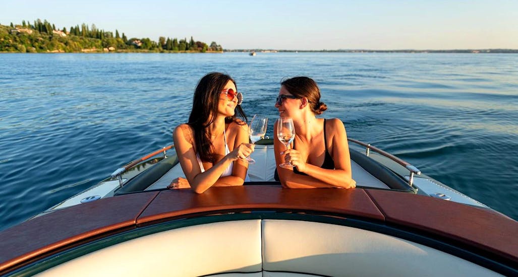 Dos amigos disfrutando de una bebida en el barco durante la excursión vespertina en barco por el Lago de Garda occidental desde Sirmione.