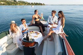 Un gruppo di amici si gode un aperitivo a bordo durante un Giro in barca lungo la costa ovest del Lago di Garda.