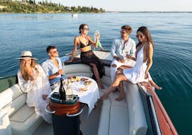 Un groupe d'amis qui profite d'un apéritif à bord pendant une balade en bateau le long de la côte ouest du Lac de Garda avec Sirmione Boats.