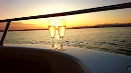 Due calici di vino con tramonto mozzafiato sullo sfondo a bordo di un motoscafo di Sirmione Boats durante un giro in barca al tramonto lungo la penisola di Sirmione. 