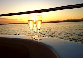 Zwei Gläser Wein mit atemberaubendem Sonnenuntergang im Hintergrund auf dem Motorboot von Sirmione Boats während einer Bootstour an der Halbinsel von Sirmione bei Sonnenuntergang.