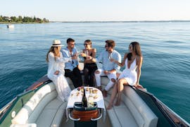 Un gruppo di amici si gode un aperitivo durante la gita in barca privata sul lago di Garda lungo la penisola di Sirmione con Garda Tours con Garda Tours.