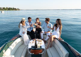 Un gruppo di amici si gode un aperitivo durante la gita in barca privata sul lago di Garda lungo la penisola di Sirmione con Garda Tours con Garda Tours.