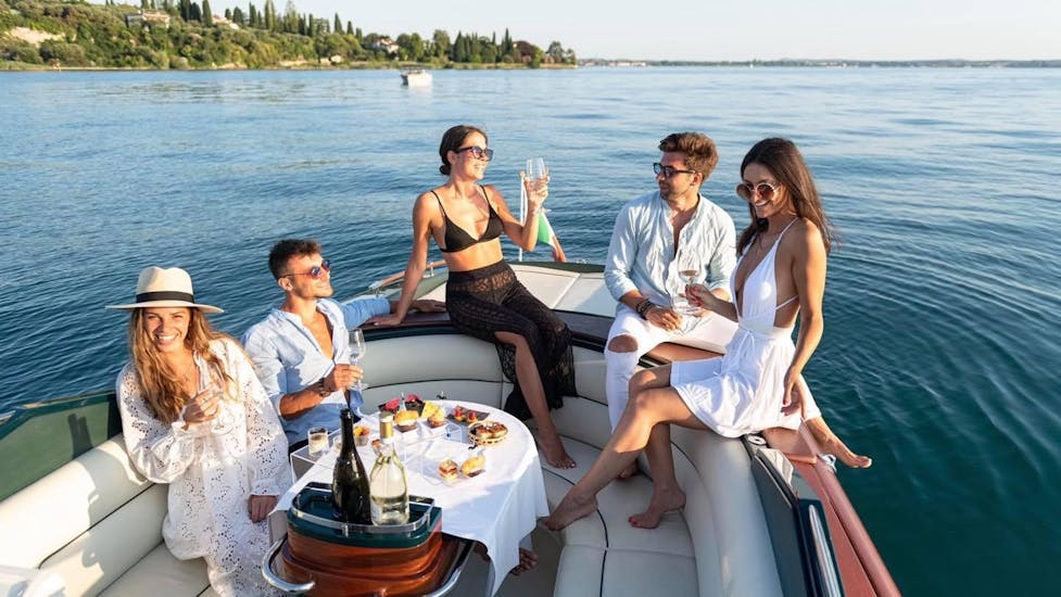 A group of friends is enjoying an aperitif on the boat during the Private Boat Trip to Isola del Garda & Sirmione Peninsula.