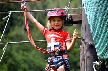 Een jong meisje dat plezier heeft tijdens het touwenparkour in het avonturenpark bij de Noce River met Extreme Waves.