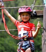 A young girl is having fun during the Ropes Course in the Adventure Park by the Noce River.