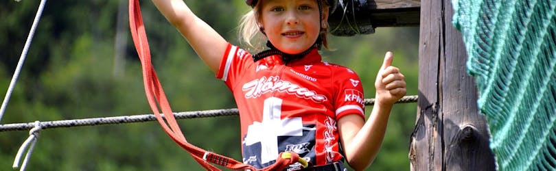 A young girl is having fun during the Ropes Course in the Adventure Park by the Noce River.