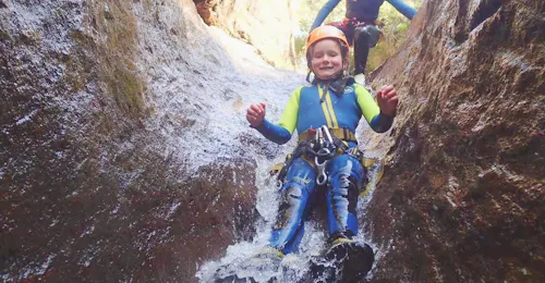 Canyoning in Ribeira das Cales auf Madeira für Anfänger mit Madeira Adventure Kingdom. Ein Mädchen rutscht beim Canyoning in der Ribeira das Cales mit Madeira Adventure Kingdom.