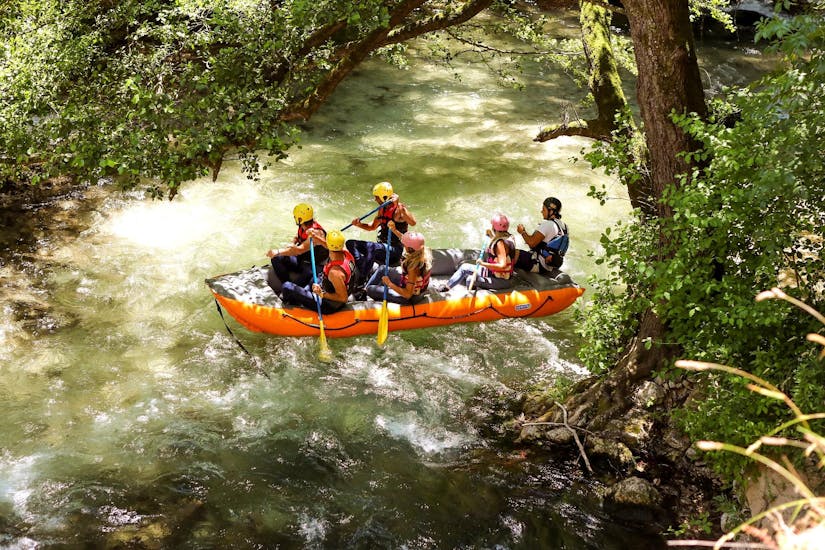 Una famiglia pagaia a bordo di un gommone godendosi la natura incontaminata durante un tour in rafting nel fiume Corno - percorso lungo con Rafting Umbria. 