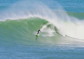 Se ve a un surfista montando una ola durante sus clases particulares de surf en la playa de Bidart, en Bidart, con la escuela de surf Le Fil Bleu.