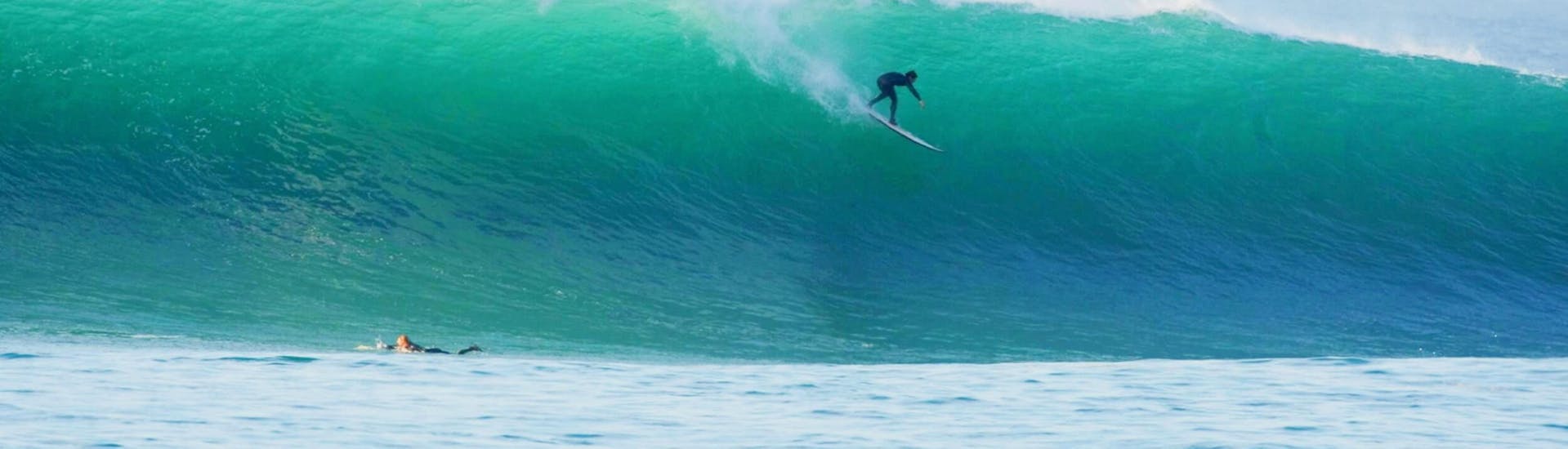 Surfeur surfant une énorme vague pendant ses cours de surf privés sur la plage de Bidart à Bidart avec Le Fil Bleu.