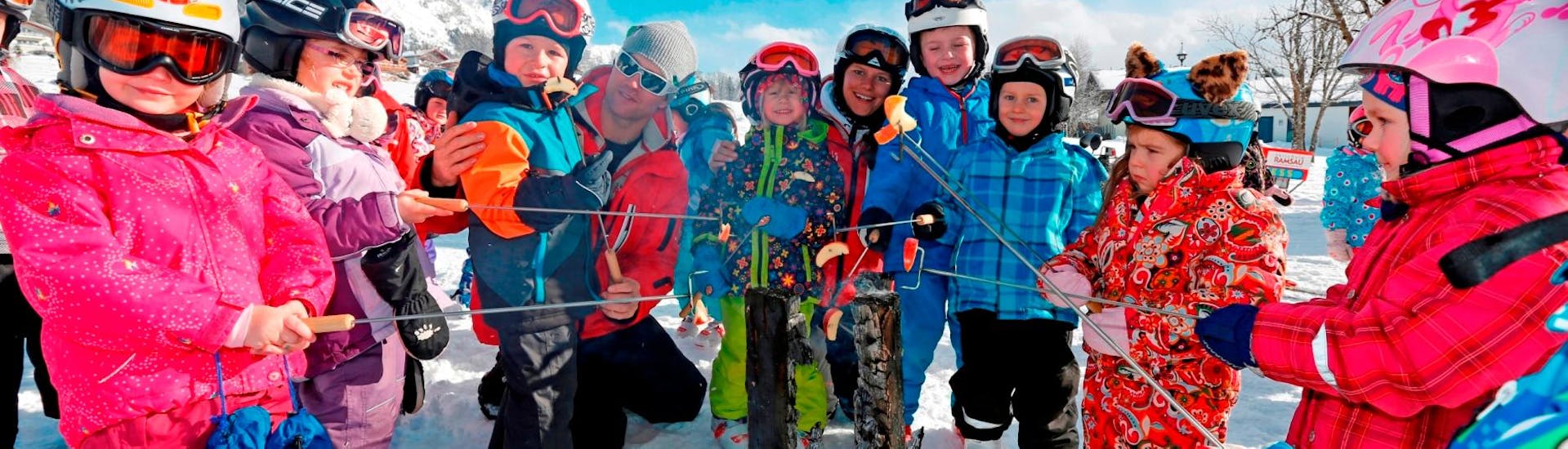 Eine Gruppe von Kindern röstet Äpfel während ihres Kinder-Skikurses für Anfänger mit der Skischule Ramsau.