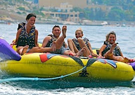 Eine Gruppe geht mit Sun & Fun Watersports Malta auf eine Fahrt mit dem Crazy Sofa in St. George's Bay.