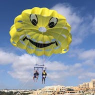 Dos personas disfrutan de un paseo en parasailing en la bahía de St. George con Sun & Fun Watersports Malta.