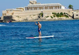 Un uomo fa stand up paddling con una tavola di Sun & Fun Watersports Malta.
