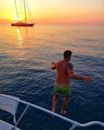 Durante un paseo privado en barco al atardecer en Cefalù, con visitas turísticas, y con Sea Land Tours Cefalù, un niño salta al mar.