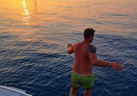 Lors de la Balade privée en bateau au coucher du soleil à Cefalù avec Baignade avec Sea Land Tours Cefalù un homme plonge dans l'eau.