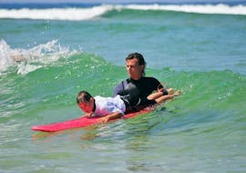 Kid with the instructor surfing during his surf lessons on Mimizan Beach with Mimizan Surf Academy.