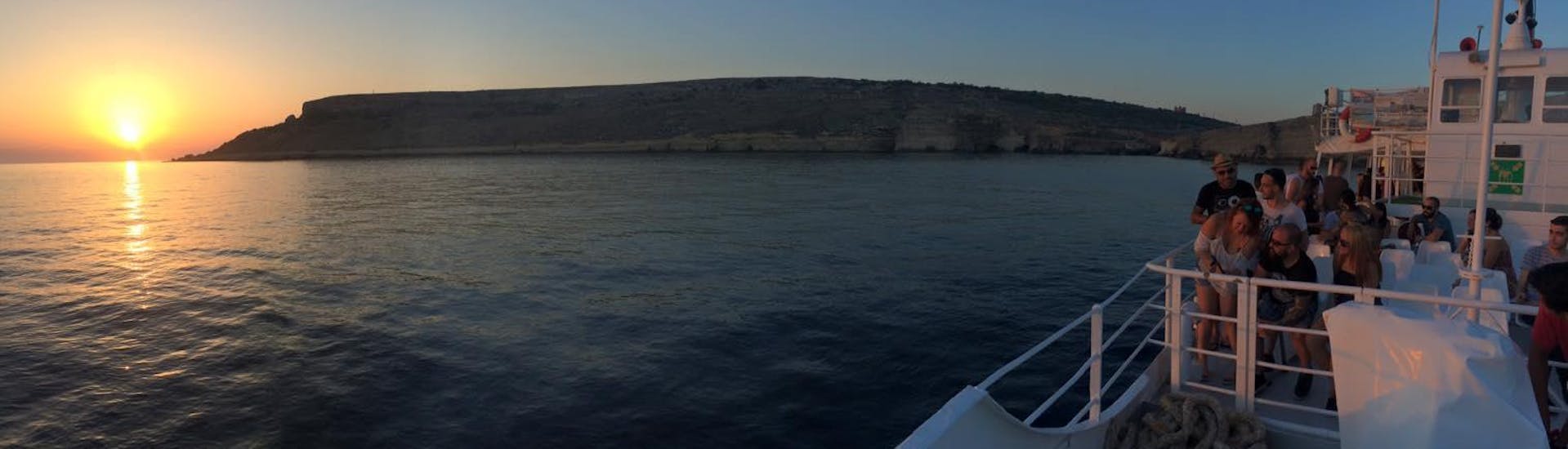 Eine Gruppe von Menschen beobachtet bei der Bootsfahrt zur Blauen Lagune bei Sonnenuntergang mit Hornblower Cruises den Sonnenuntergang am Horizont.