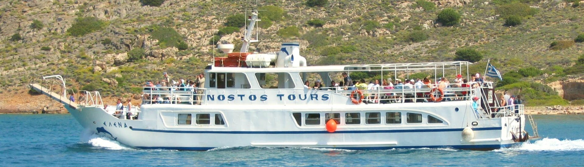 Das Boot, das für die Bootstour nach Spinalonga mit Schwimmen von Nostos Cruises verwendet wird, fährt durch das tiefblaue Wasser vor der Küste Kretas.