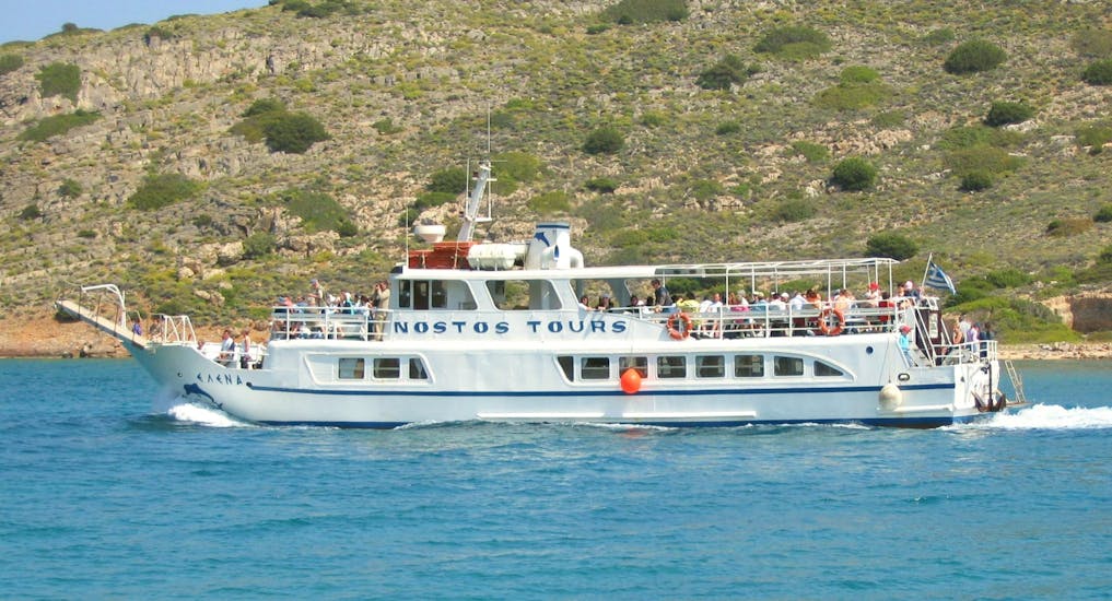 La barca utilizzata per la gita in barca all'isola di Spinalonga con bagno da Nostos Cruises naviga nelle limpide acque blu al largo della costa cretese.