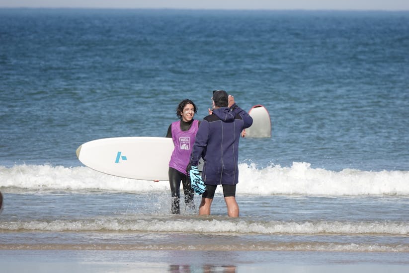 A young girl gets out of the water with her surfboard.