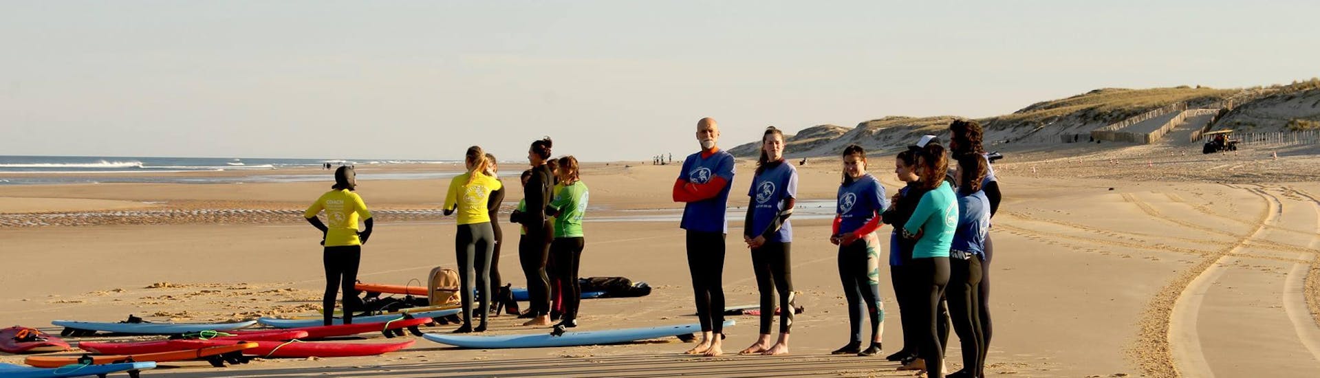 Group of friends on Lacanau Beach doing surfing lessons with HCL Lacanau.