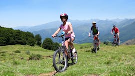 A young girl is cycling across a meadow with her bike rented from the bike hire at Skischule & Bikeverleih AGE Ötz-Hochötz in the Oetztal Valley.