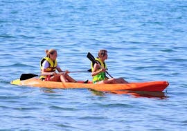 Dos niñas van en un canoas de mar en la bahía de Ammoudara con H2O Water Sports Heraklion.