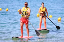Two persons go stand up paddling in Ammoudara Beach with h2o Water Sports Heraklion. 