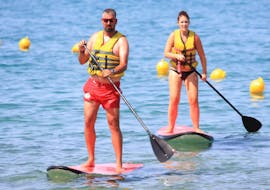 Two persons go stand up paddling in Ammoudara Beach with h2o Water Sports Heraklion. 