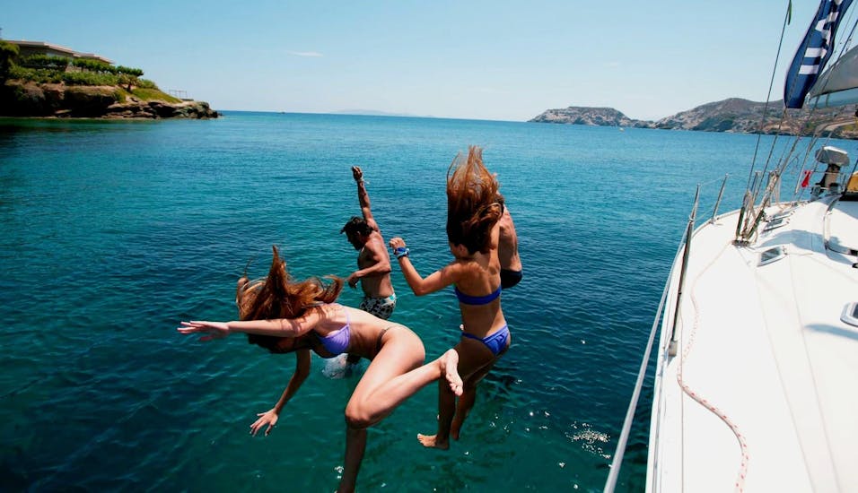 Een groep meiden spingt van de boot tijdens de zeiltocht van een halve dag naar Dia-eiland met snorkelen met Altersail Heraklion.