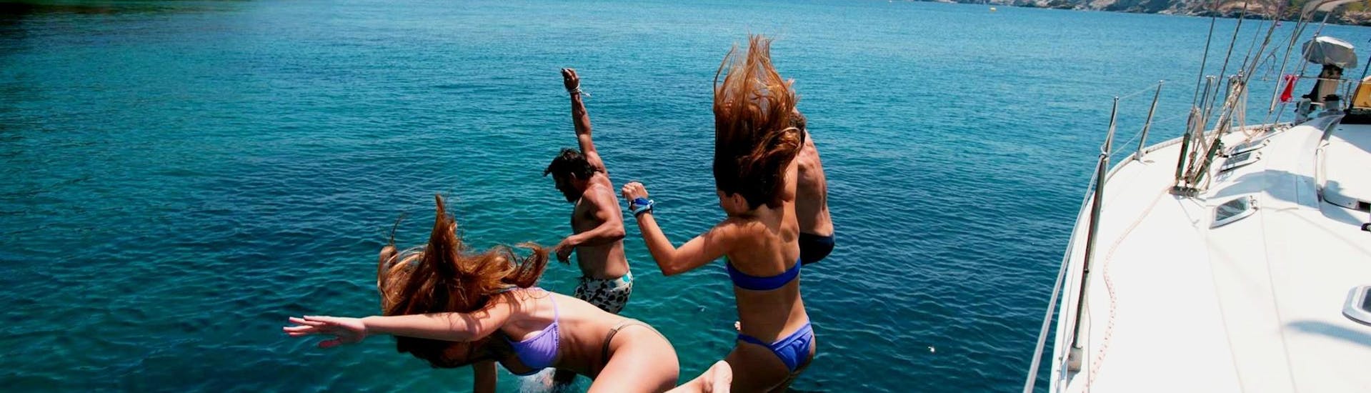 Een groep meiden spingt van de boot tijdens de zeiltocht van een halve dag naar Dia-eiland met snorkelen met Altersail Heraklion.