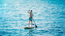 A young boy is taking advantage of the SUP hire on Stafilia Beach by Sabina's Watersport Rhodes to explore the clear waters along the coast of Lardos.