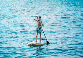 Un ragazzo sta noleggiando un SUP sulla spiaggia di Stafilia tramite Sabina Watersport Rhodes per esplorare le limpide acque lungo la costa di Lardos.
