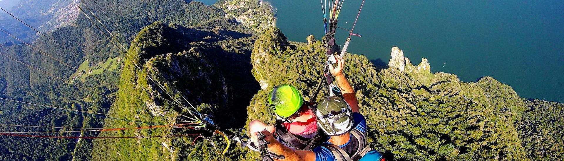 Un chico y un piloto están volando en el aire mientras disfrutan del impresionante panorama del lago durante un parapente en tándem desde Monte Pizzoccolo, sobre el lago de Garda, con Brixia Flying Lake Garda.