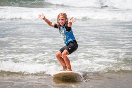 A young girl is surfing her first waves thanks to her surfing lessons for kids on La Savane Beach with Capbreton Surfer School.