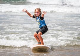 A young girl is surfing her first waves thanks to her surfing lessons for kids on La Savane Beach with Capbreton Surfer School.