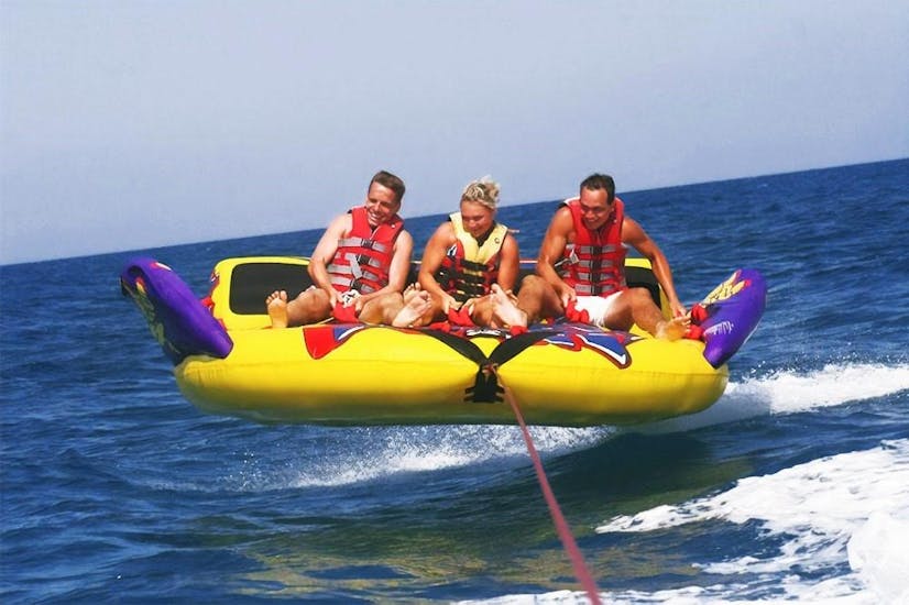 A group of friends have fun on a Crazy Sofa on Rethymno Beach with Popeye Watersports. 