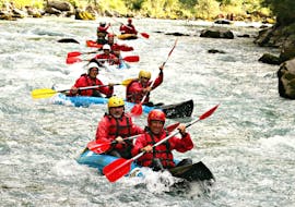 An adventurous group is paddling across the rapids in their the canoe-raft on the river Stura di Demonte with KE Rafting Roccasparvera.