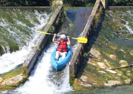 Een kajakker glijdt van een natuurlijke waterglijbaan tijdens hun kanoverhuur op de rivier de Tarn - Emotion 11 km tocht met Canoë Aigue Vive Gorges du Tarn.