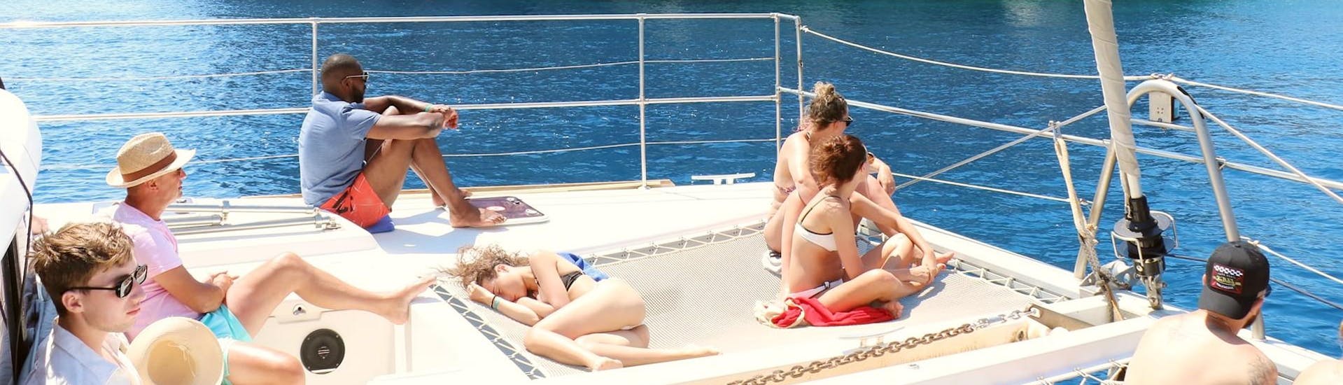 Delle persone sdraiate al sole durante la gita in catamarano a Kallithea Springs ed alla Baia di Anthony Quinn con Catamaran Cruises.