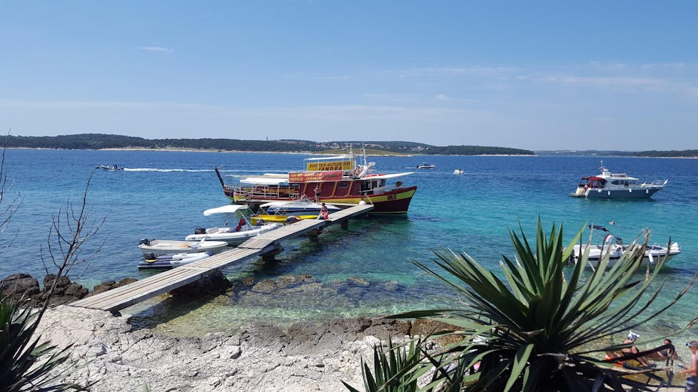 Das Boot von Medulin Excursions liegt an der Anlegestelle, während die Leute für die Bootstour zum Kap Kamenjak ab Medulin mit Schwimmen an Bord gehen.